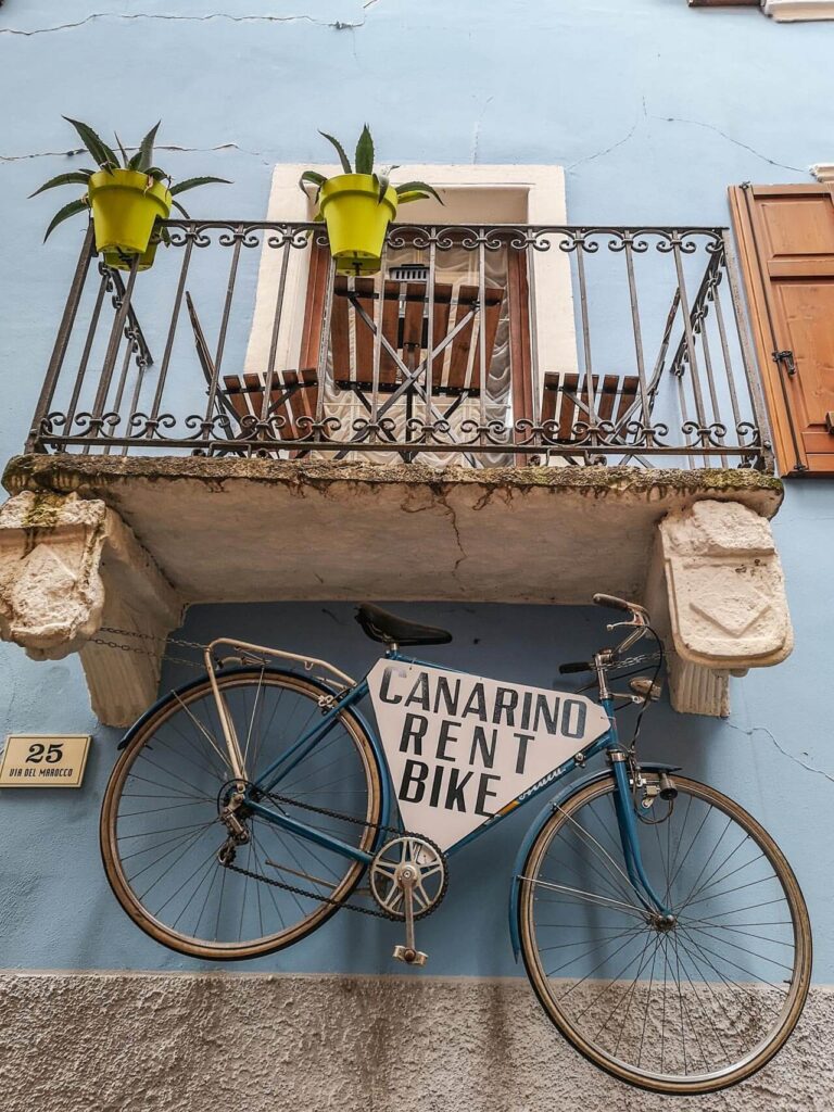Sehenswürdigkeiten in Riva del Garda am nördlichen Gardasee in Italien: Das Marokko-Viertel. Das Bild zeigt ein Fahrrad in der Via del Marocco, das am Balkon eines blauen Hauses aufgehängt ist