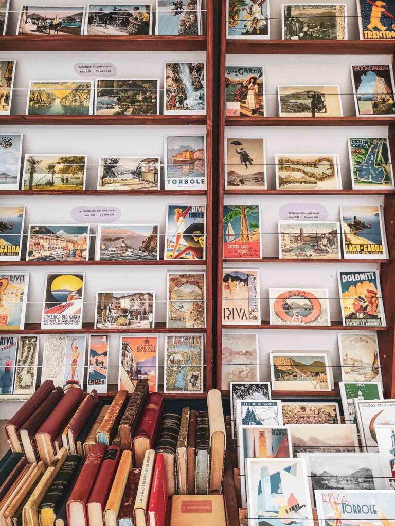 Riva del Garda am nördlichen Gardasee in Italien: Das Bild zeigt eine Wand mit Vintage-Postkarten mit Gardasee-Motiven in einem Antiquariat in der Altstadt von Riva del Garda