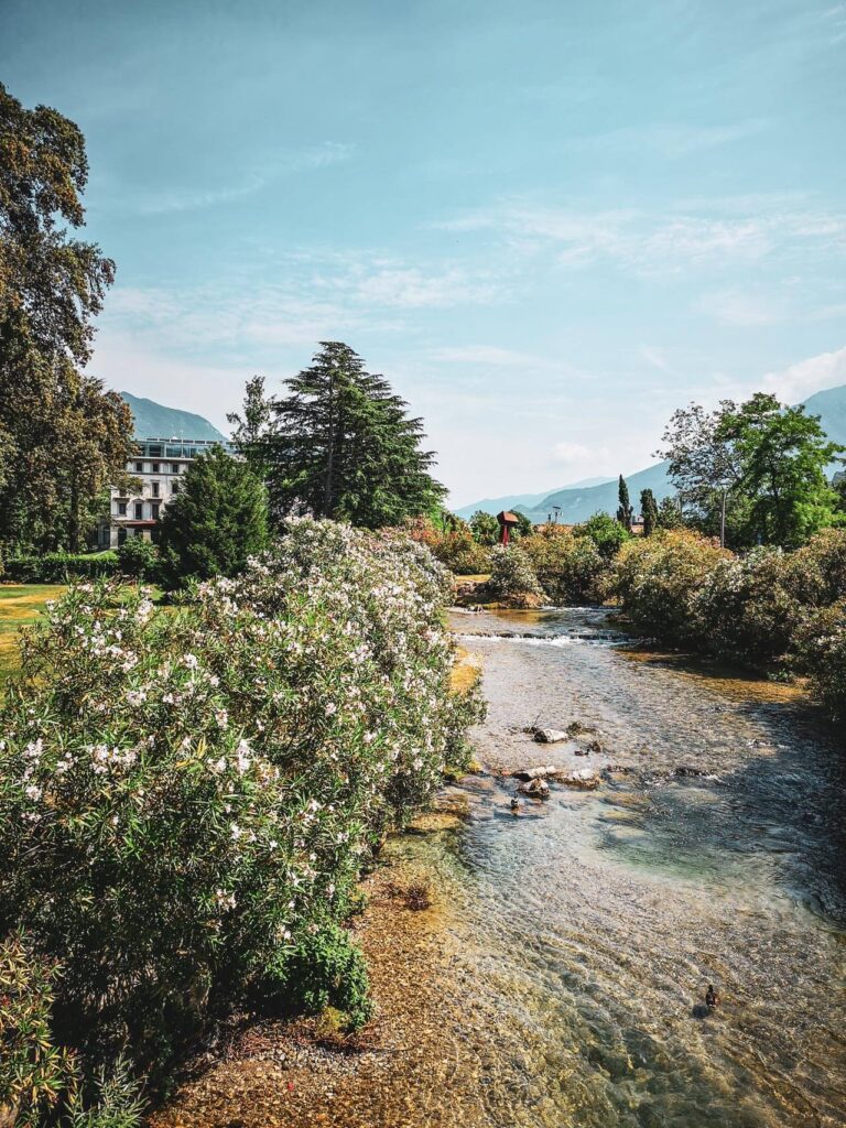 Freizeitaktivitäten in Riva del Garda am nördlichen Gardasee in Italien: Das Bild zeigt den Parco dell'Ora Riva, einen kleinen Park mit Blick auf den Fluss und das elegante Hotel Lido Palace
