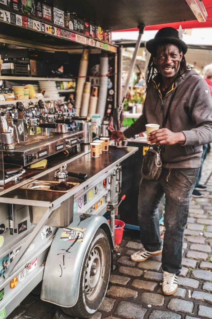 Reisetipps Hamburg: Barista Jessy Greaves am Kaffeewagen auf dem Hamburger Fischmarkt lächelt in die Kamera – beliebter Foodie-Spot für Kaffee in Hamburg