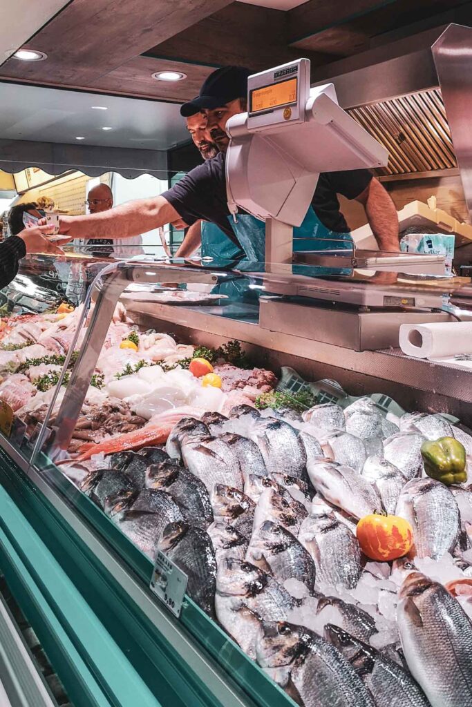 Reisetipps Hamburg: Fischstand auf dem Hamburger Fischmarkt mit frischem Fisch in der Auslage und geschäftigen Verkäufern – typische Food-Szene auf dem Traditionsmarkt