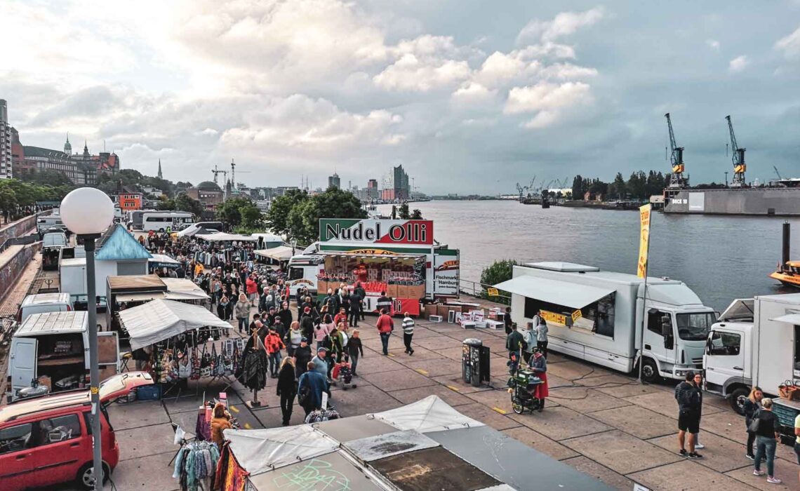 Hamburger Fischmarkt bei Sonnenaufgang mit Blick auf belebte Marktstände an der Elbe in Hamburg – traditioneller Wochenmarkt, Sehenswürdigkeit und beliebtes Reiseziel