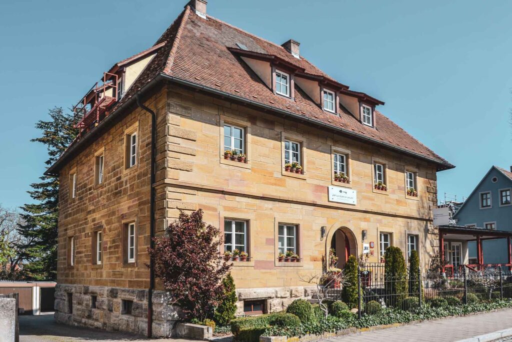 Das Hotel Villa Mittermeier in Rothenburg ob der Tauber. Das Bild zeigt das Sandsteingebäude mit dem Haupteingang vor strahlend blauem Himmel
