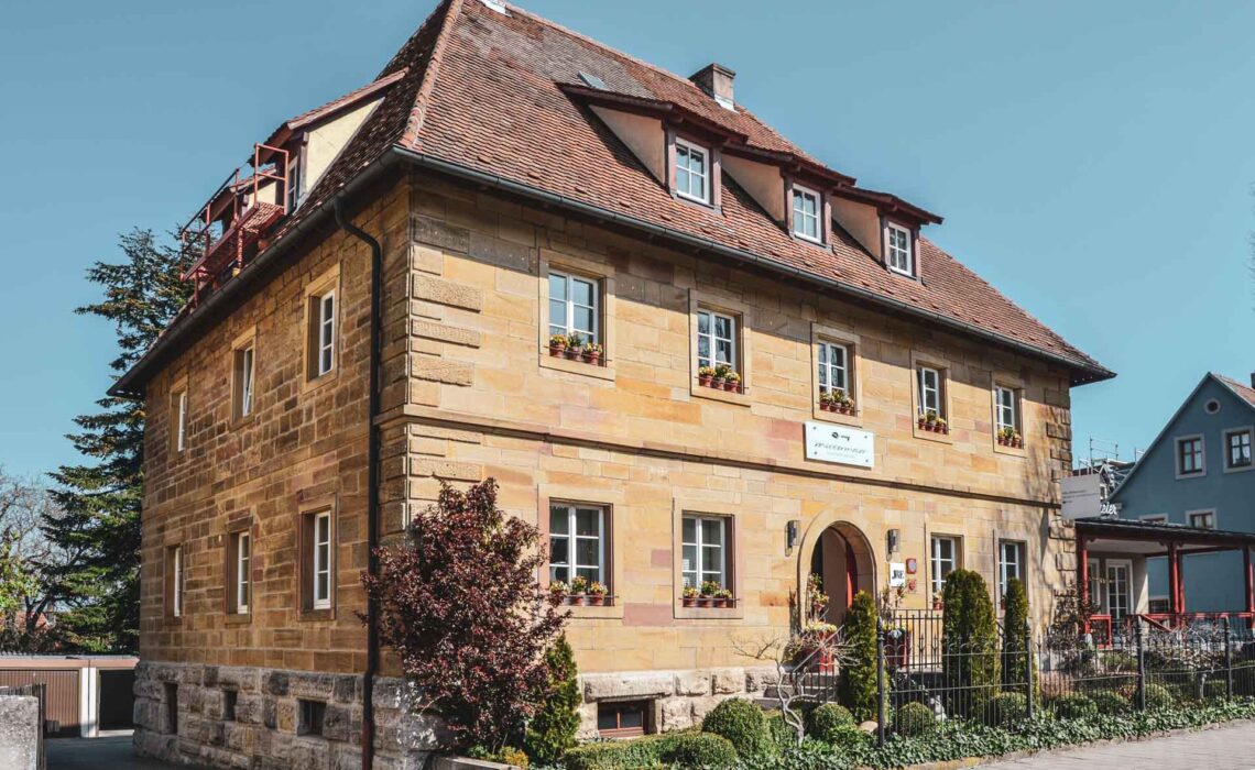 Das Hotel Villa Mittermeier in Rothenburg ob der Tauber. Das Bild zeigt das Sandsteingebäude mit dem Haupteingang vor strahlend blauem Himmel