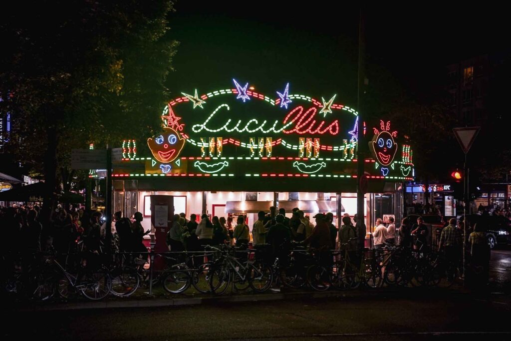 Hamburg Foodtipps: Currywurst essen in Hamburgs berühmtesten Imbiss an der Reeperbahn in St. Pauli. Der Imbissstand bei Nacht mit bunten Lichtern