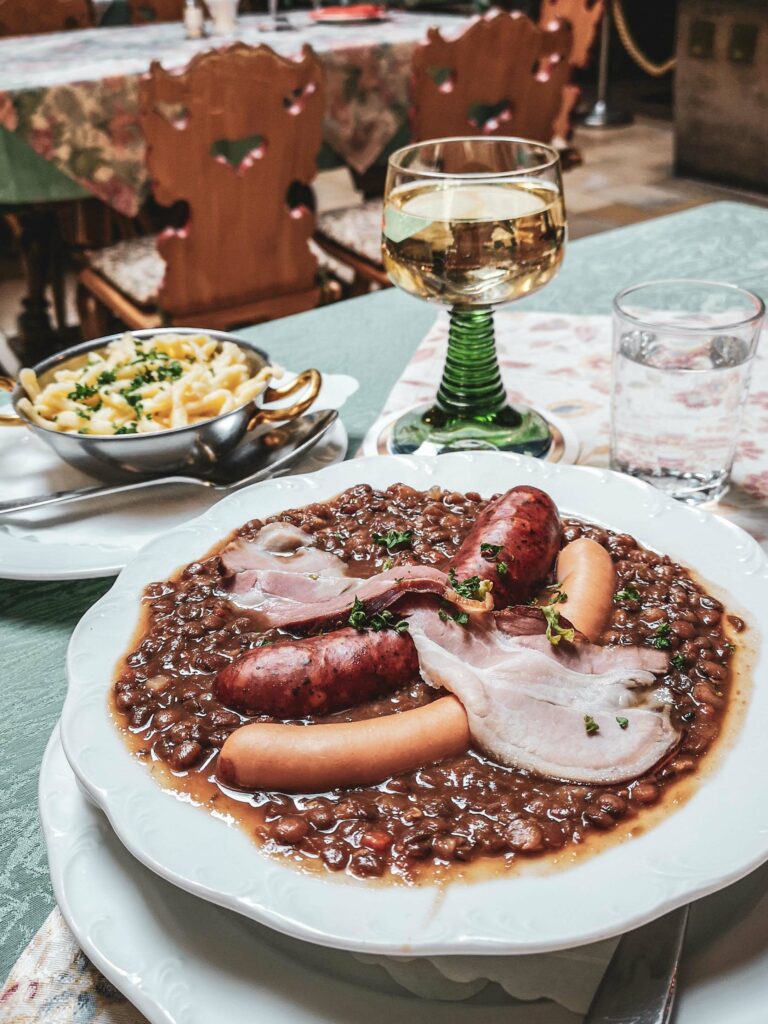 Deftiges Mittagessen im Baumeisterhaus in Rothenburg ob der Tauber: Linseneintropf mit Wuerstchen und Spaetzle, dazu ein Glas Weißwein aus Franken