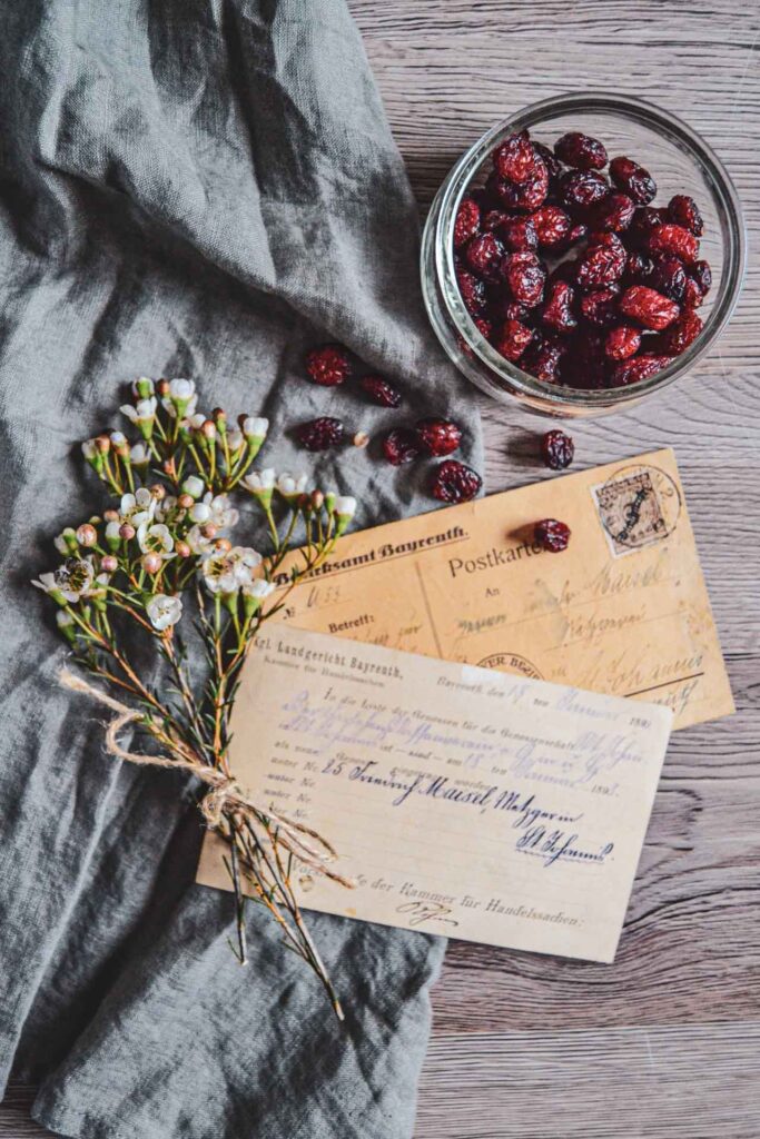 Vintage-Postkarten mit Winterblumen und Cranberrys auf einer grauen Stoffserviette.