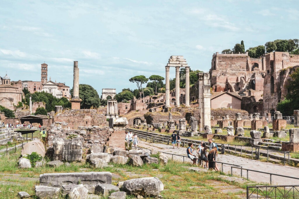 Italien im Sommer: Das Forum Romanum. Blick auf weiße Steinsäulen, Steine und einen gepflasterten Weg mit Absperrungen