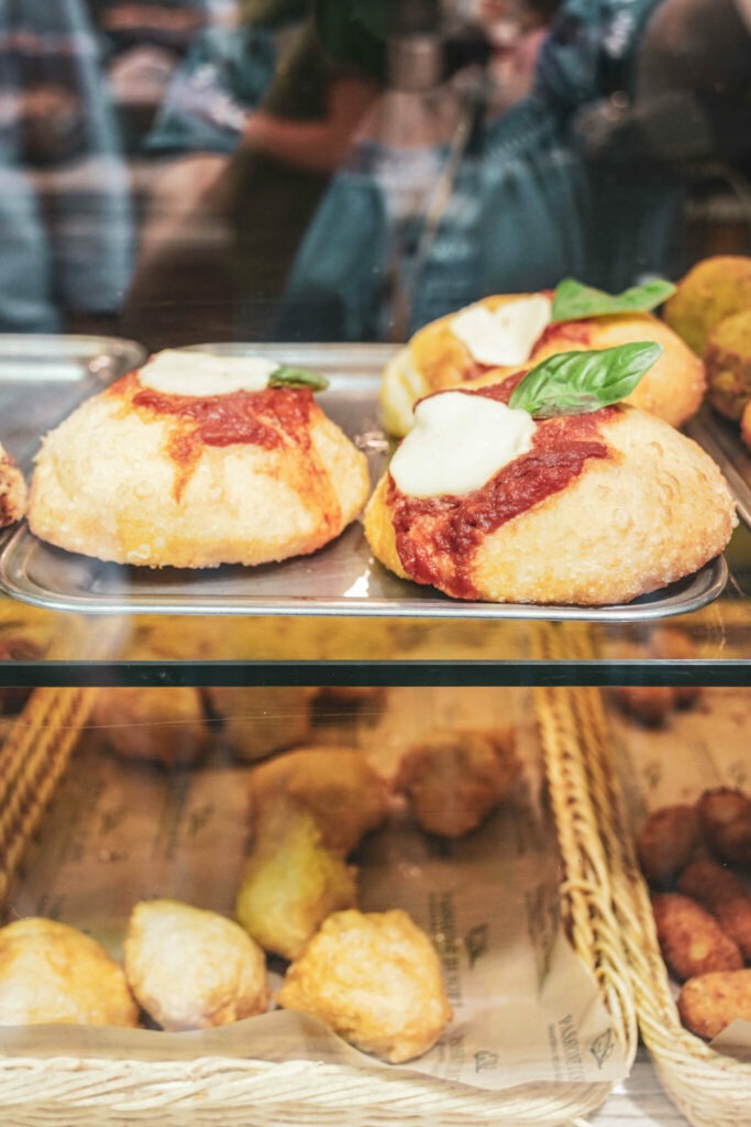 Italien im Sommer: Pizza montanara oder auch Pizza fritta: Frittierte Pizza mit Tomaten, Mozzarella und Basilikum. Typisches Streetfood in Neapel in einer Ladentheke im Straßenverkauf neben anderen frittierten lokalen Speisen