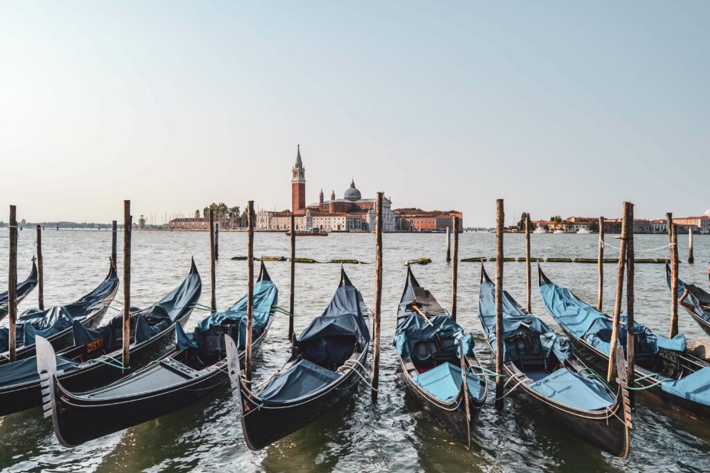 Venedig: Der Blick auf die Benediktiner-Abtei San Gorgio Maggiore auf der gleichnamigen Insel in der Lagune von Venedig vom Bacino di San Marco aus. Im Vordergrund sind blaue venezianische Gondeln zu sehen