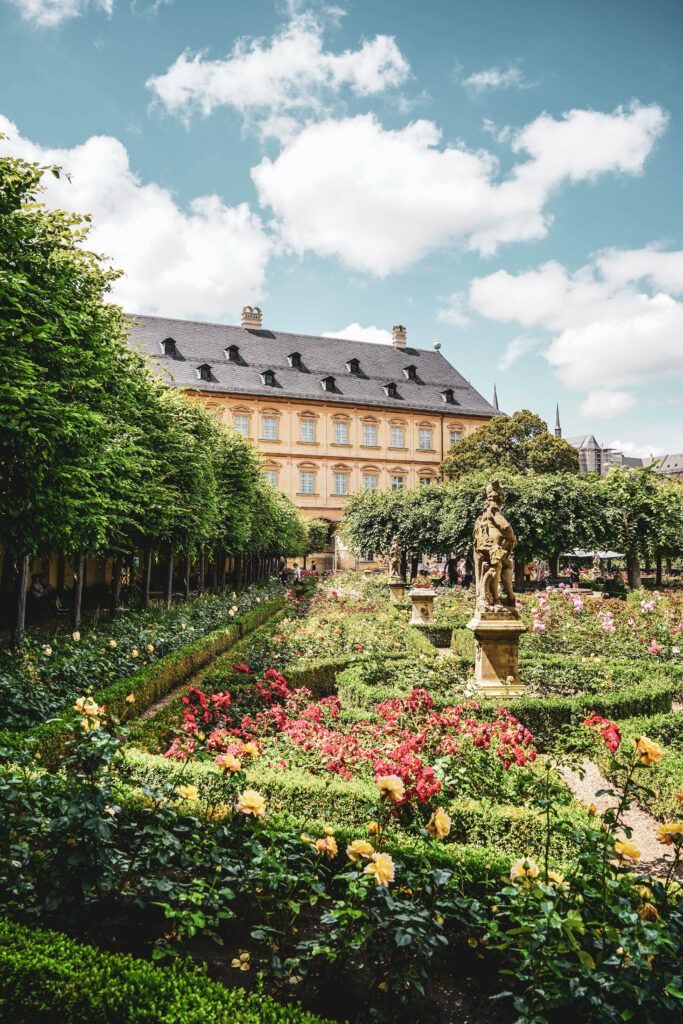 Rosengarten Bamberg im Sommer bei blauem Himmel mit Wolken und pinkfarbenen Rosen,, angelegt im Barockstil mit symmetrischen Hecken und Skulpturen