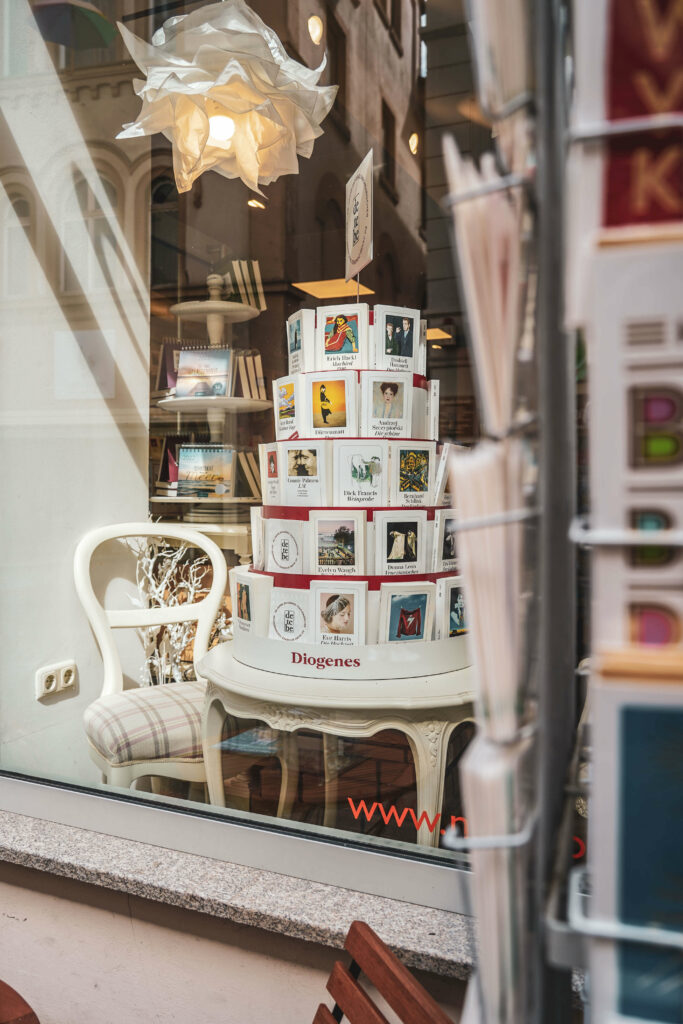 Schaufenster der Buchhandlung Collibri in der Langen Strasse in Bamberg mit einer dekorierten Torte aus weißen Diogenes-Taschenbuechern und einem weißen Stuhl daneben