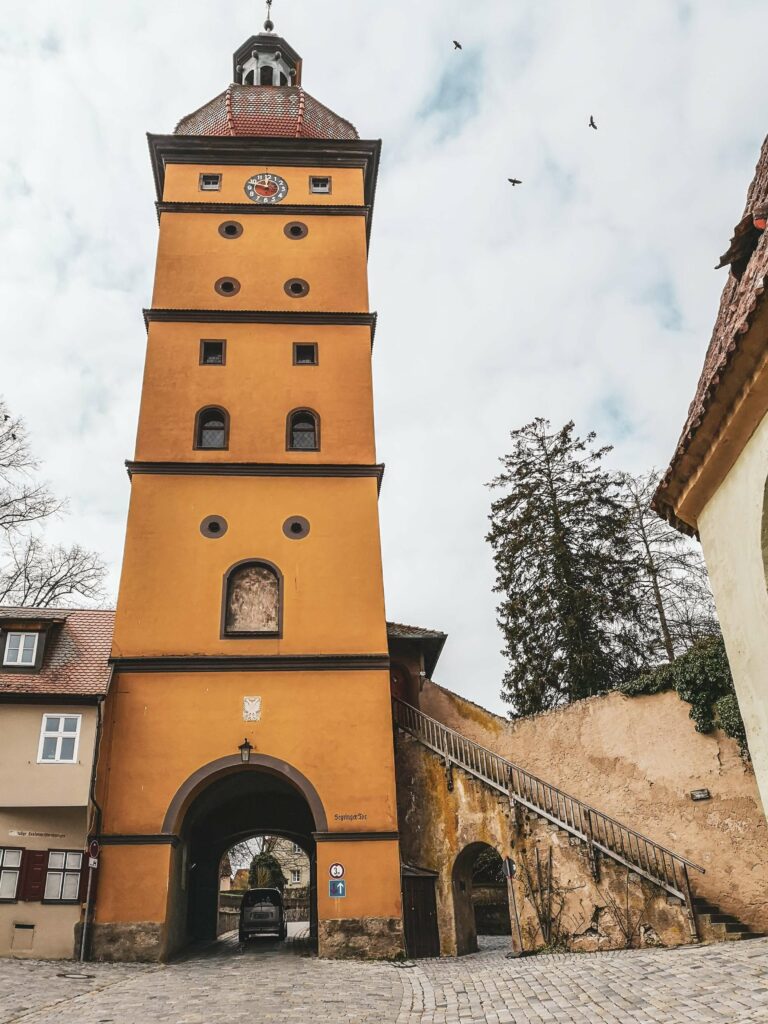 Turm des Segringer Tors. Historisches Stadttor in Dinkelsbuehl in Orange mit Durchfahrt fuer Autos.