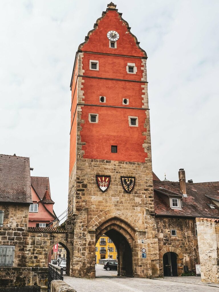 Das rote Woernitztor in Dinkelsbuehl mit Sandstein und Wappen inmitten der mittelalterlichen Stadtmauer