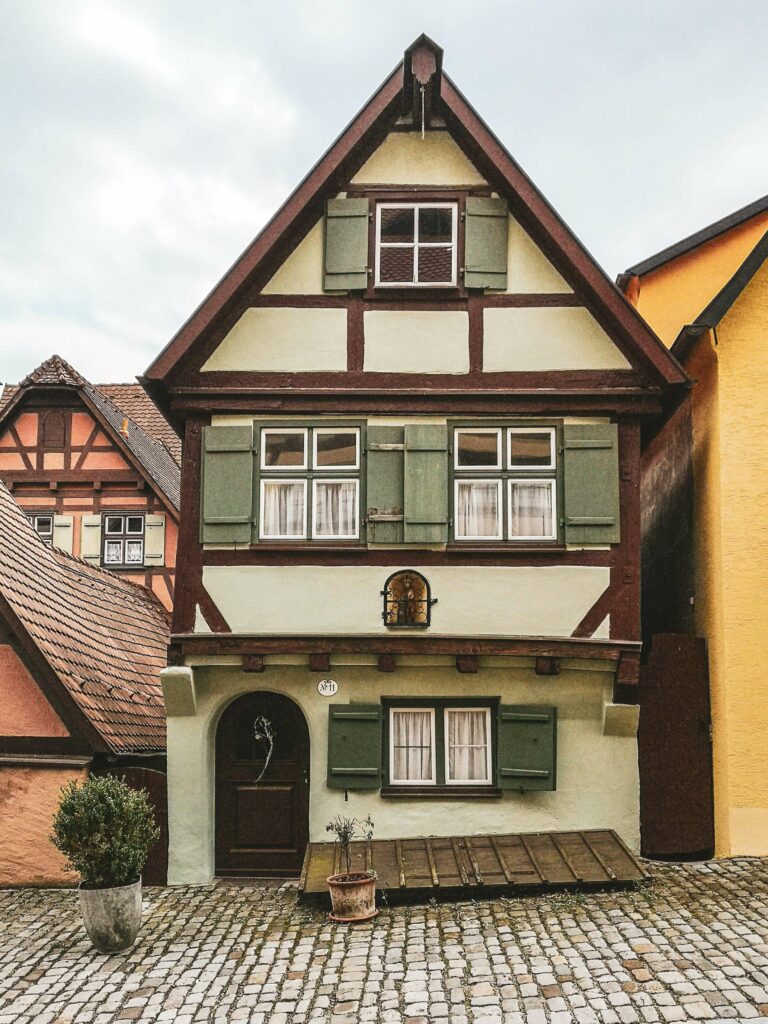 Kleines Fachwerkhaus in Dinkelsbuehl in Hellgruen mit dunkelgruenen Fensterlaeden und dunklem Holz in der Altstadt.