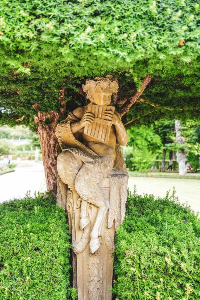 Reisetipps und Sehenswürdigkeiten Würzburg: Statue des Hirtengottes Pan in einem Baum im Hofgarten der Würzburger Residenz im Sommer