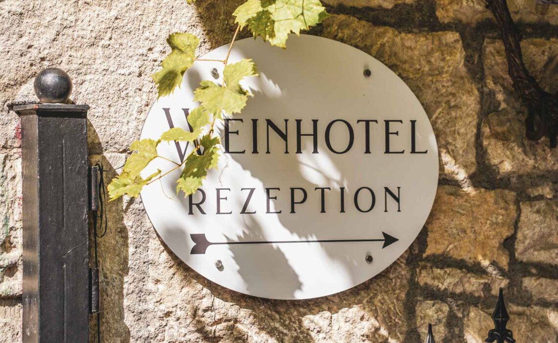 Das Weinhotel Oechsle & Brix in Sommerhausen. Schild am an der Sandsteinfassade des Hotels mit Aufschrift Weinhotel – Rezeption