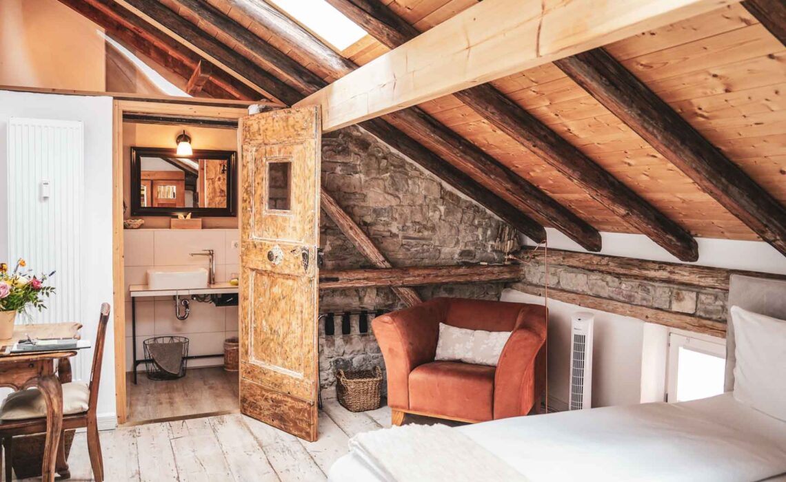 Das Weinhotel Oechlse & Brix in Sommerhausen im Maintal: Das Superior Zimmer Ortega im Dachgeschoss mit Fachwerkbalken und Blick ins Badezimmer