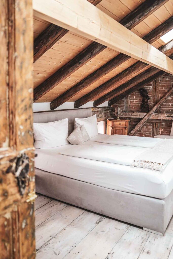 Das Weinhotel Oechlse & Brix in Sommerhausen am Main: Blick ins Superior Zimmer Ortega vom Badezimmer aus auf das gemütliche Doppelbett unter den Dachschrägen aus Holz und Fachwerk
