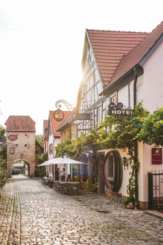 Das Winzerdorf Sommerhausen am Main: Die idyllische Maingasse mit dem Maintor und dem Weinhotel Oechsle und Brix in der Abendsonne