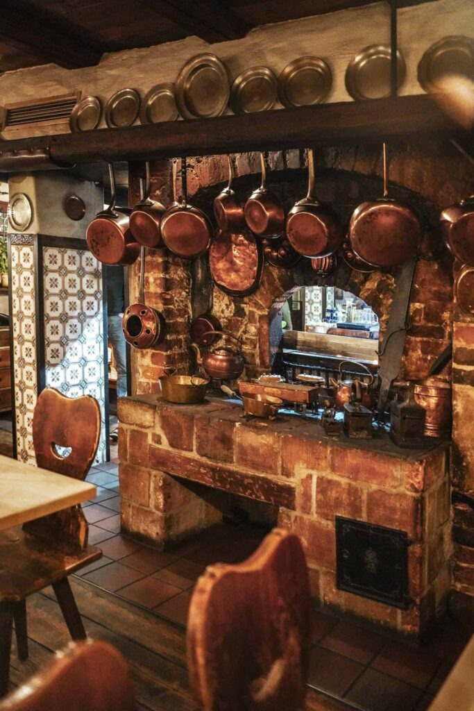 Die offene Feuerstelle aus dem 16. Jh. im Gasthaus Zum gulden Stern in Nürnberg mit Backsteinumrahmung und unzähligen Kupferpfannen im historischen Gastraum.