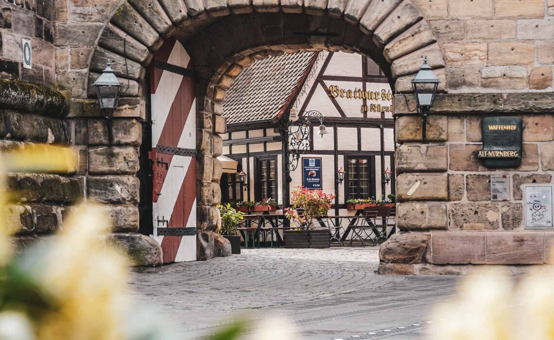 Das Bratwurstglöcklein im Nürnberger Handwerkerhof mit Blick von der Hauptstraße aus durch das Sandsteintor