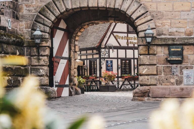 Das Bratwurstglöcklein im Nürnberger Handwerkerhof mit Blick von der Hauptstraße aus durch das Sandsteintor