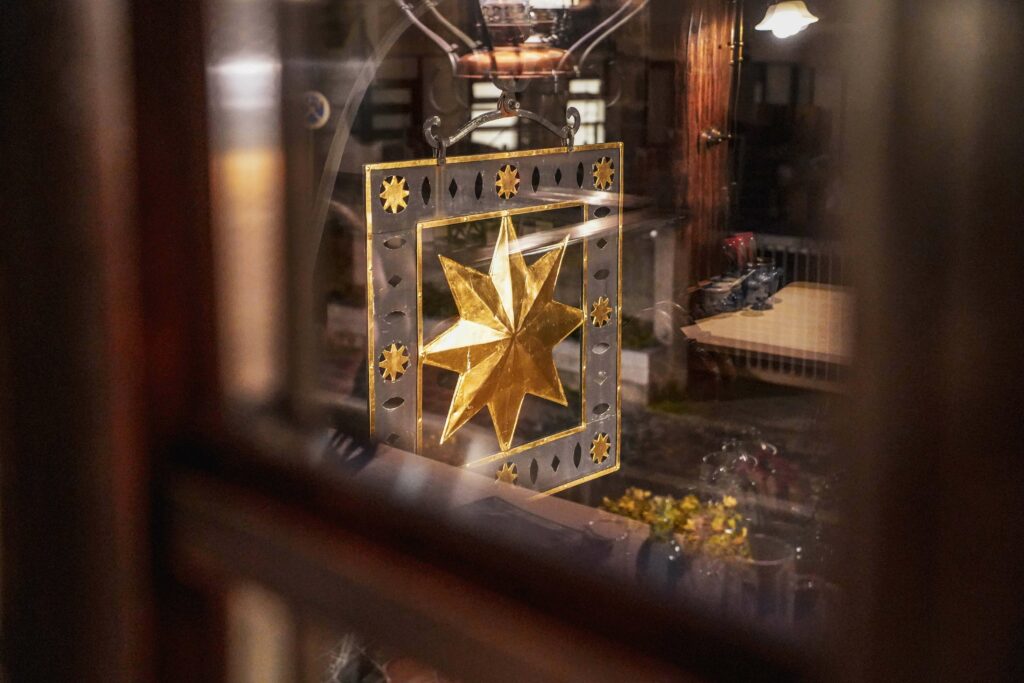 Das Wirtshausschild der Bratwurstküche Zum gulden Stern in Nürnberg zeigt einen vergoldeten Stern in einem Viereck, fotografiert aus dem Fenster im Obergeschoss des Gasthauses.