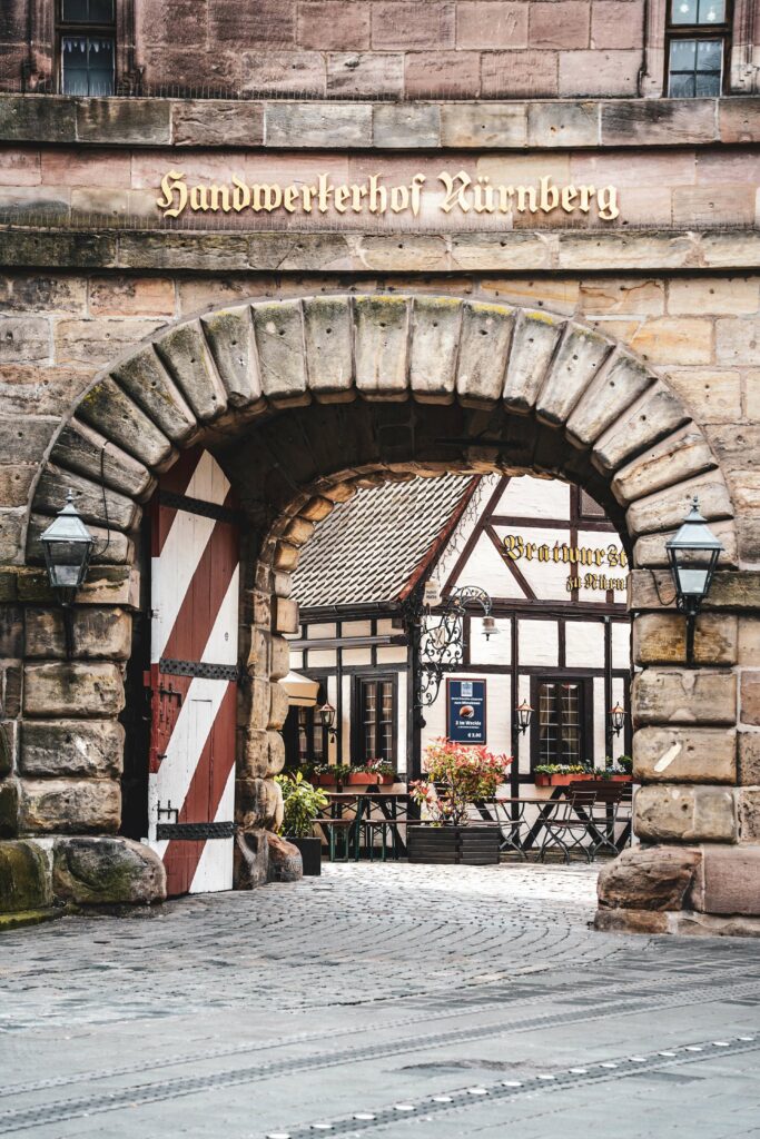 Blick durch das Tor des Handwerkerhofs Nürnberg auf das historische Fachwerkhaus des Bratwurstglöckle