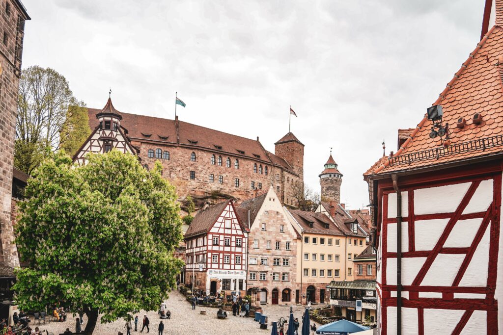 Blick auf den Platz am Tiergärtnertor in Nürnberg von der Stadtmauer aus. Im Hintergrund ist die Kaiserburg zu sehen, im Vordergrund verschiedene Fachwerkhäuser