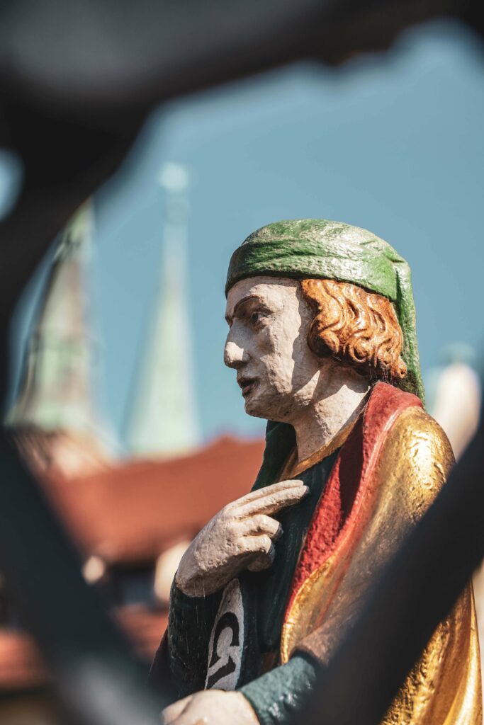 Figur auf dem Schönen Brunnen auf dem Nürnberger Hauptmarkt. Im Hintergrund sind die Kirchtürme von St. Sebaldus zu sehen