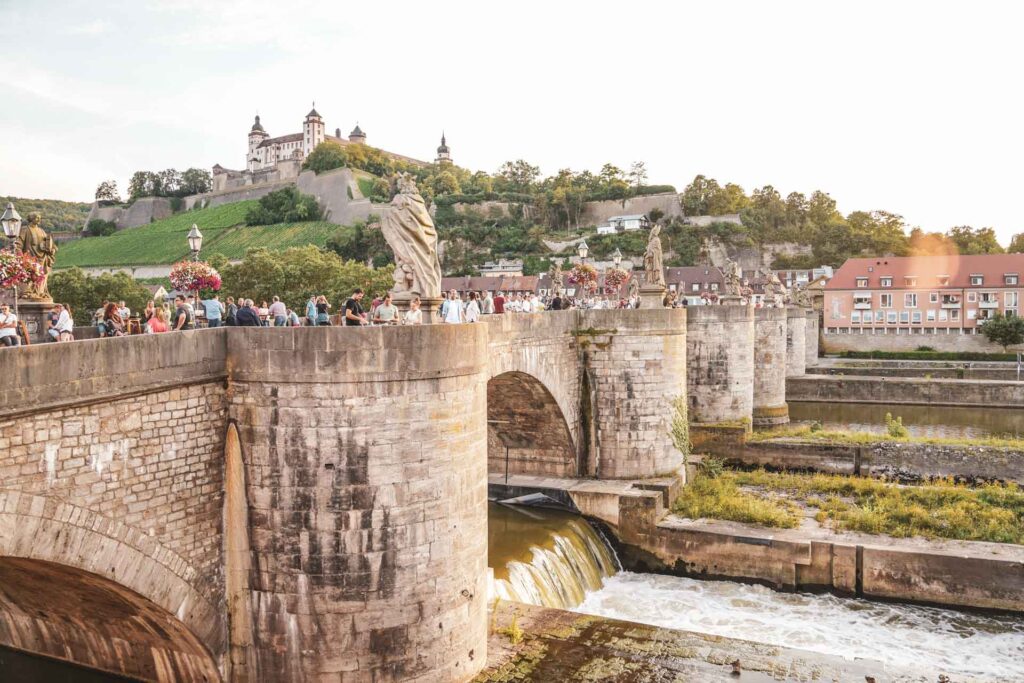 Foodtipps Würzburg: Ausblick auf die Alte Mainbruecke und die Festung Marienberg bei Sonnenuntergang im Sommer
