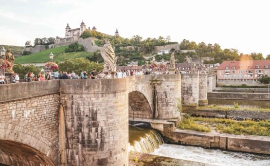 Foodtipps Würzburg: Ausblick auf die Alte Mainbruecke und die Festung Marienberg bei Sonnenuntergang im Sommer