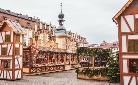 Weihnachtsmarkt in Bamberg: Geschmückte traditionelle Marktstände auf dem Maximiliansplatz mit Schwibbögen und einer Miniatur des Alten Rathauses