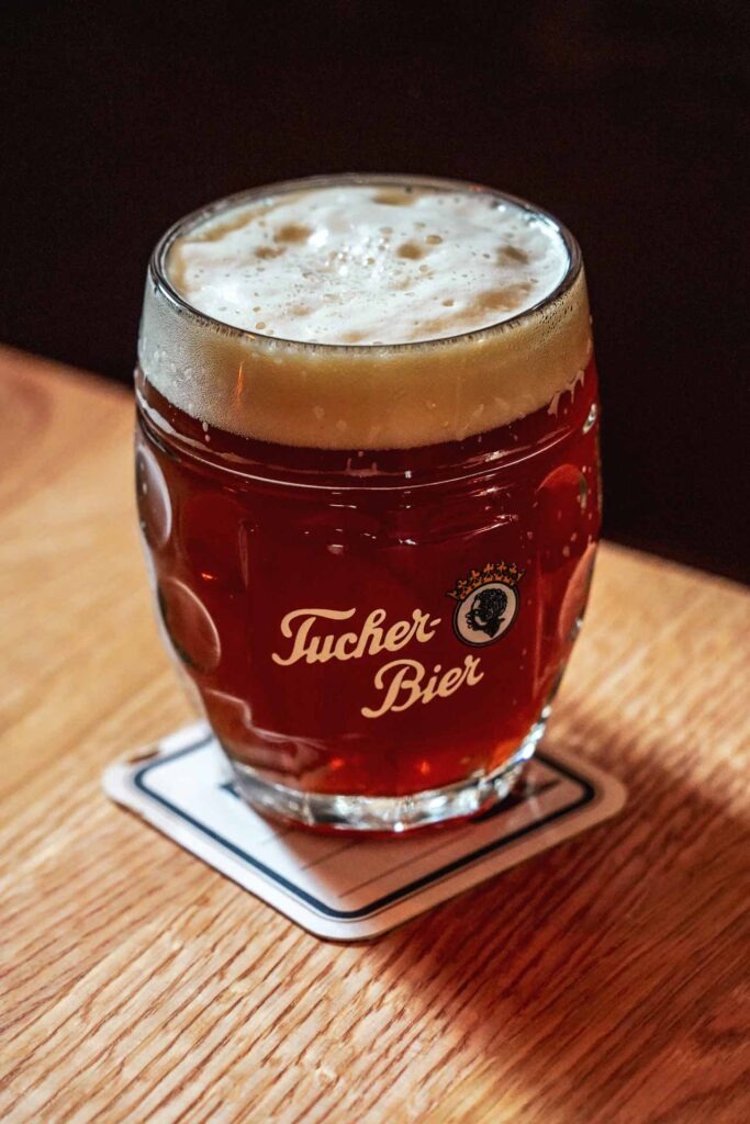 Foodtipps Nürnberg – Nürnberger Rotbier im Wirtshaus Tucher-Bräu in Nürnberg im Glaskrug mit Aufschrift Tucher-Bräu