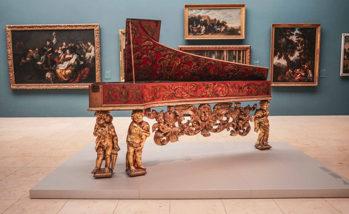 Sehenswürdigkeiten Nürnberg: Aufwendig verzierter Flügel in der Dauerausstellung Renaissance, Barock und Aufklärung des Germanischen Nationalmuseums in Nürnberg vor einer petrolblauen Wand mit Gemälden im Hintergrund