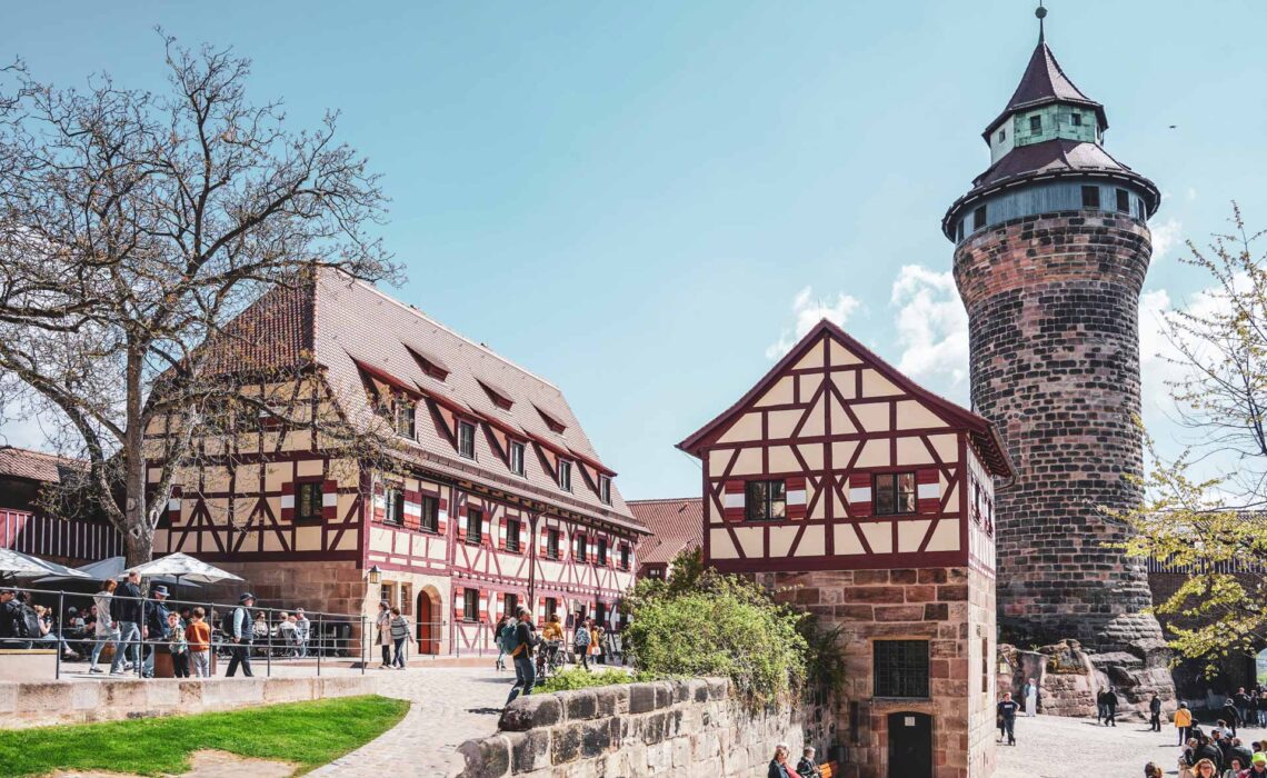 Reisetipps Nürnberg: Auf der Kaiserburg Nürnberg mit Blick auf das Brunnenhaus, den Sinwellturm und das Burgcafé, ein typisches Fachwerkhaus mit Fensterläden in Rot-Weiß