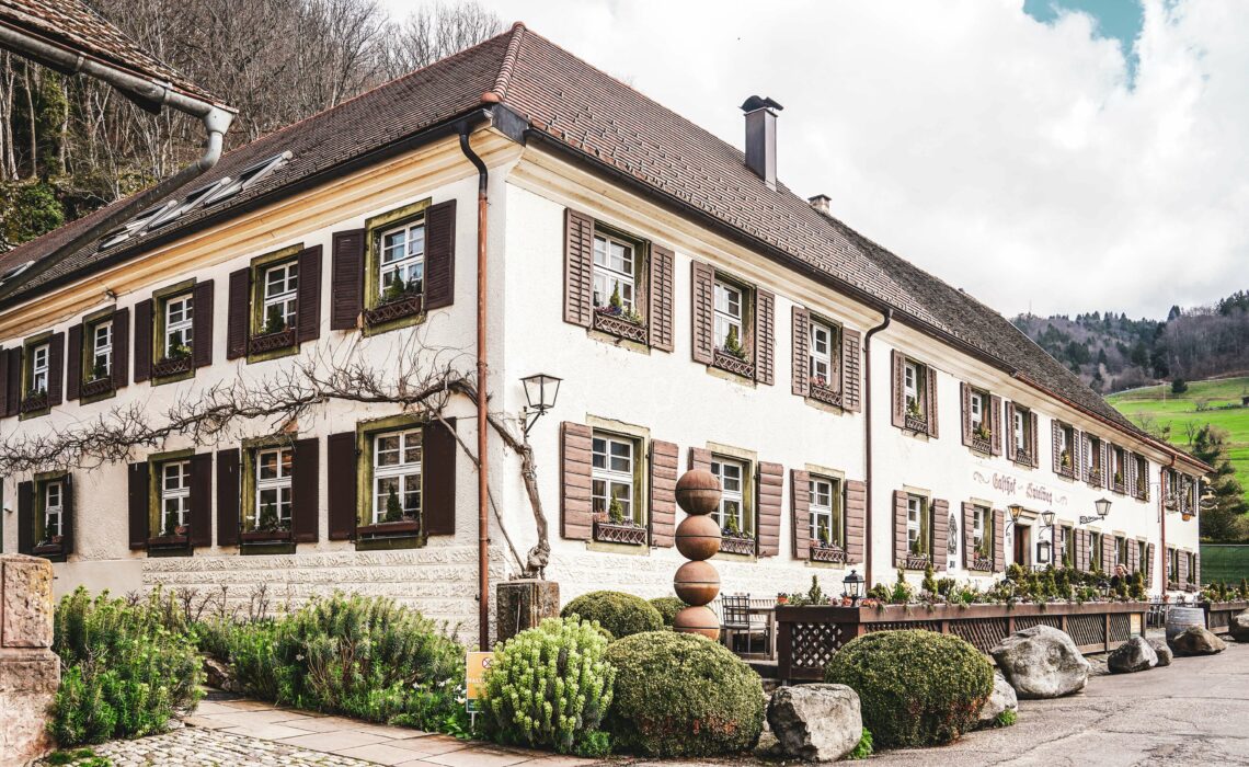 Das Romantik-Hotel Spielweg im idyllischen Münstertal im Schwarzwald im Frühling mit braunen Fensterläden und der Sonnenterrasse vor dem Hauseingang am Spielweg.