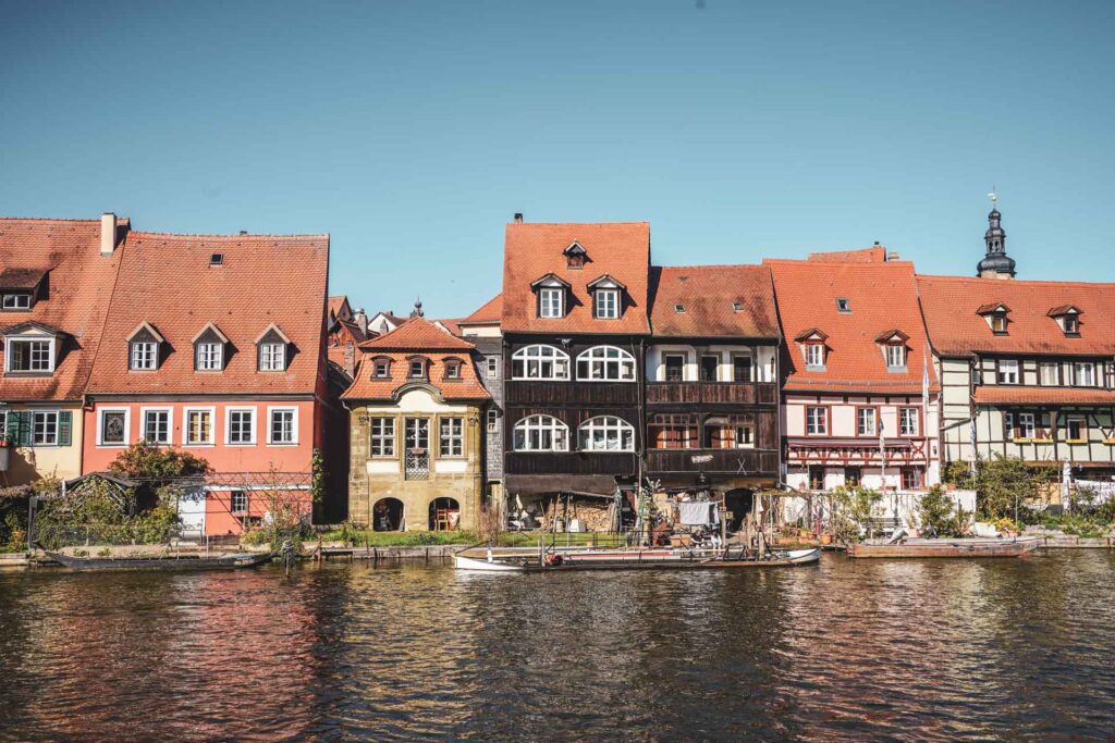 Bamberg im Frühling: Blick auf die historischen Fachwerkhäuser von Klein Venedig mit kleinen Gärten entlang des Regnitzufers in der Nachmittagssonne