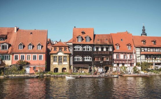 Bamberg im Frühling: Blick auf die historischen Fachwerkhäuser von Klein Venedig mit kleinen Gärten entlang des Regnitzufers in der Nachmittagssonne