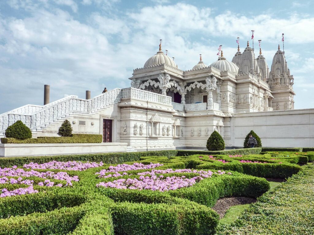 Geheimtipp für Sehenswürdigkeiten in London: Neasden Temple, der größte hinduistische Tempel Großbritanniens im Londoner Stadtteil Brent mit weißen Kuppeln und Heckengarten