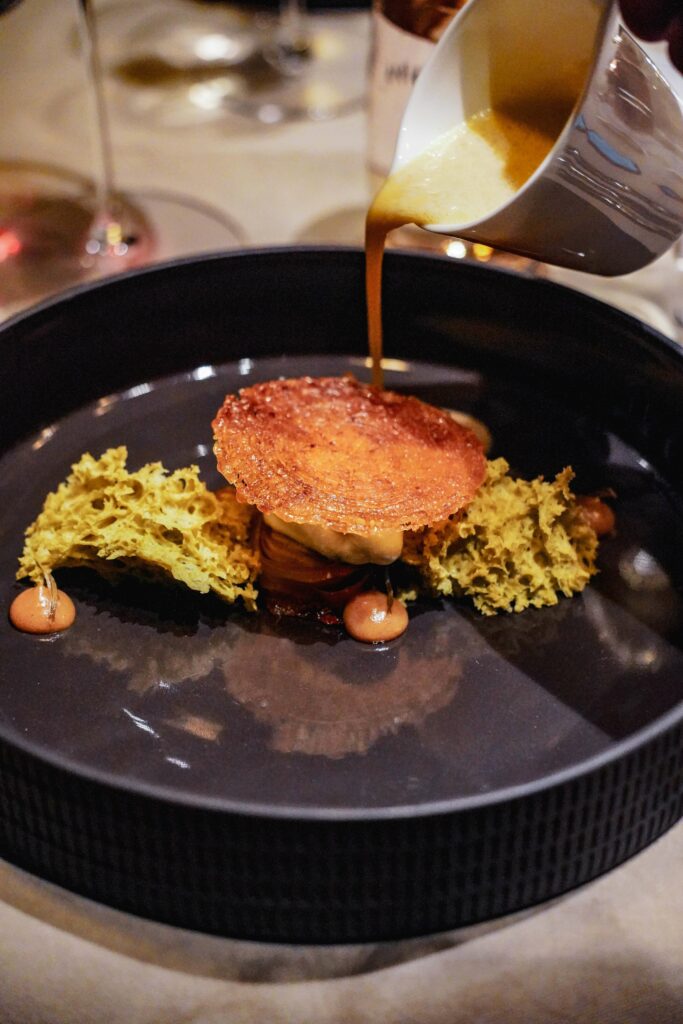 Das Dessert „Nadelwald“ des Presse-Menüs im Sterne-Restaurant KUNO in Würzburg, das gerade mit Sauerrahm aus einem Kännchen übergossen wird