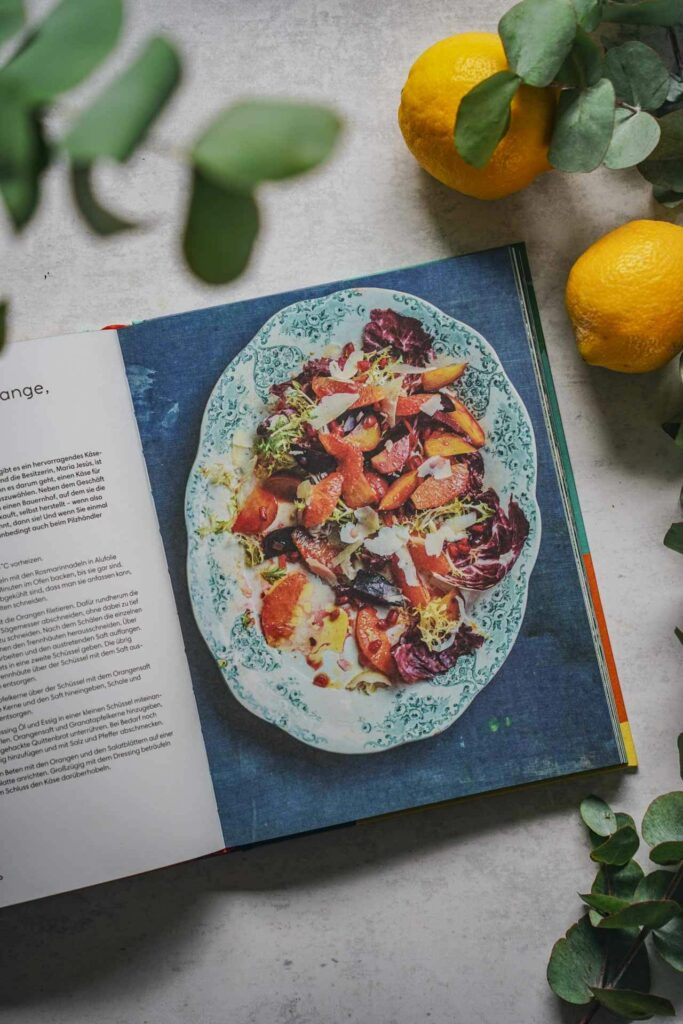 Die schönsten Kochbücher für den Sommer: Das Kochbuch Andalusien von José Pizzaro aus dem DK-Verlag. Das Bild zeigt das Rezeptfoto für Salat Salat aus Roter Bete, Blutorange, Granatapfel und Ziegenkäse, umgeben von Eukalyptus und Zitronen