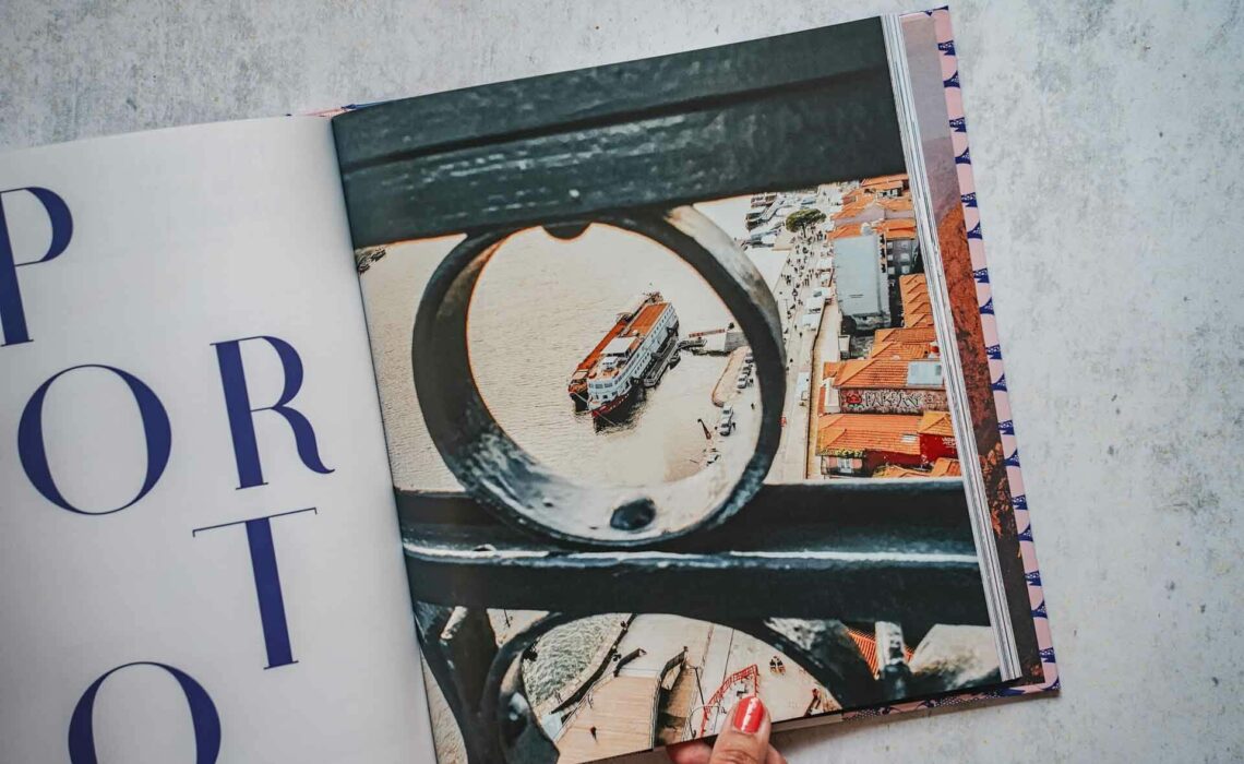 Die schönsten Kochbücher für den Sommer: Das Kochbuch Zu Gast in Portugal von Corinna Lawrenz und Motel a Miio, erschienen im Callwey Verlag. Das Bild zeigt eine Doppelseite aus dem Buch mit einem Foto des Hafens von Porto, auf der linken Seite ist der Schriftzug Porto in Blau auf Weiß zu sehen