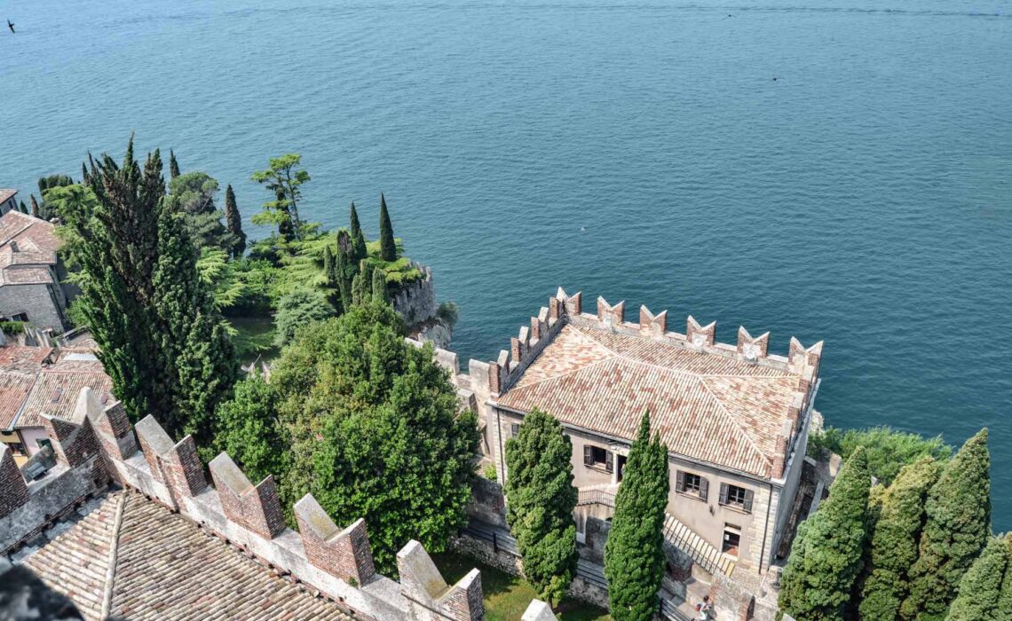 Die schönsten Orte am Gardasee: Der Palazzo dei Capitani im venezianischen Baustil unterhalb der Skaligerburg von Malcesine, im Hintergrund das türkisblaue Wasser des Gardasees