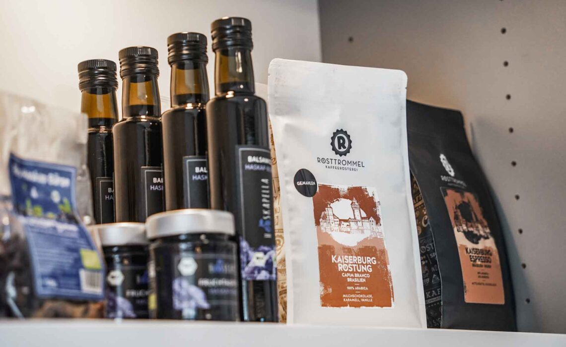 Die Genussecke in der Tourist Info im Handwerkerhof Nürnberg : Regal mit regionalen Produkten (von links nach rechts: Haskapella Fruchtaufstrich, Balsamico, Rösttrommel Kaffee)