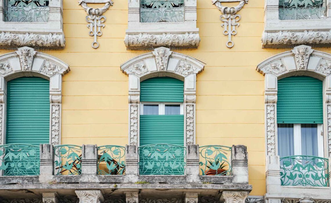 Die schönsten Orte am Gardasee: Bunte Häuserfassade in Gelb mit türkisfarbenen Rolläden in Salò
