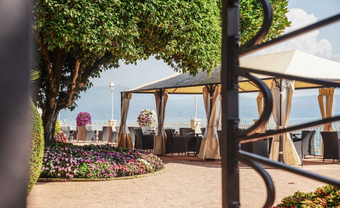Die schönsten Orte am Gardasee: Bild durch ein gusseisernes Tor in einen Garten mit Pavillon eines Luxushotels in Gardone Riviera