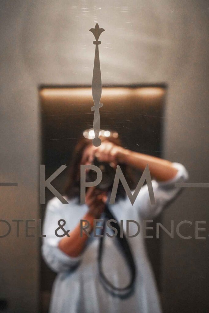 Geldermann x KPM –Launch der Bayreuther Festspiel-Cuvée zu Richard Wagners Die Meistersinger von Nürnberg 2025: Alexandra Baier von Tables & Fables macht ein Foto-Selfie in der Hotellobby vor dem Spiegel mit Schriftzug des Hotels KPM Hotel & Residences.