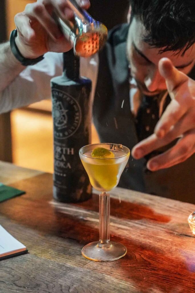 Foodtipps Hamburg: Special Performance bei den The George Martini Affairs in der DaCaio Bar im The George Hotel: Der Barkeeper beim Servieren des The George Golden Martini